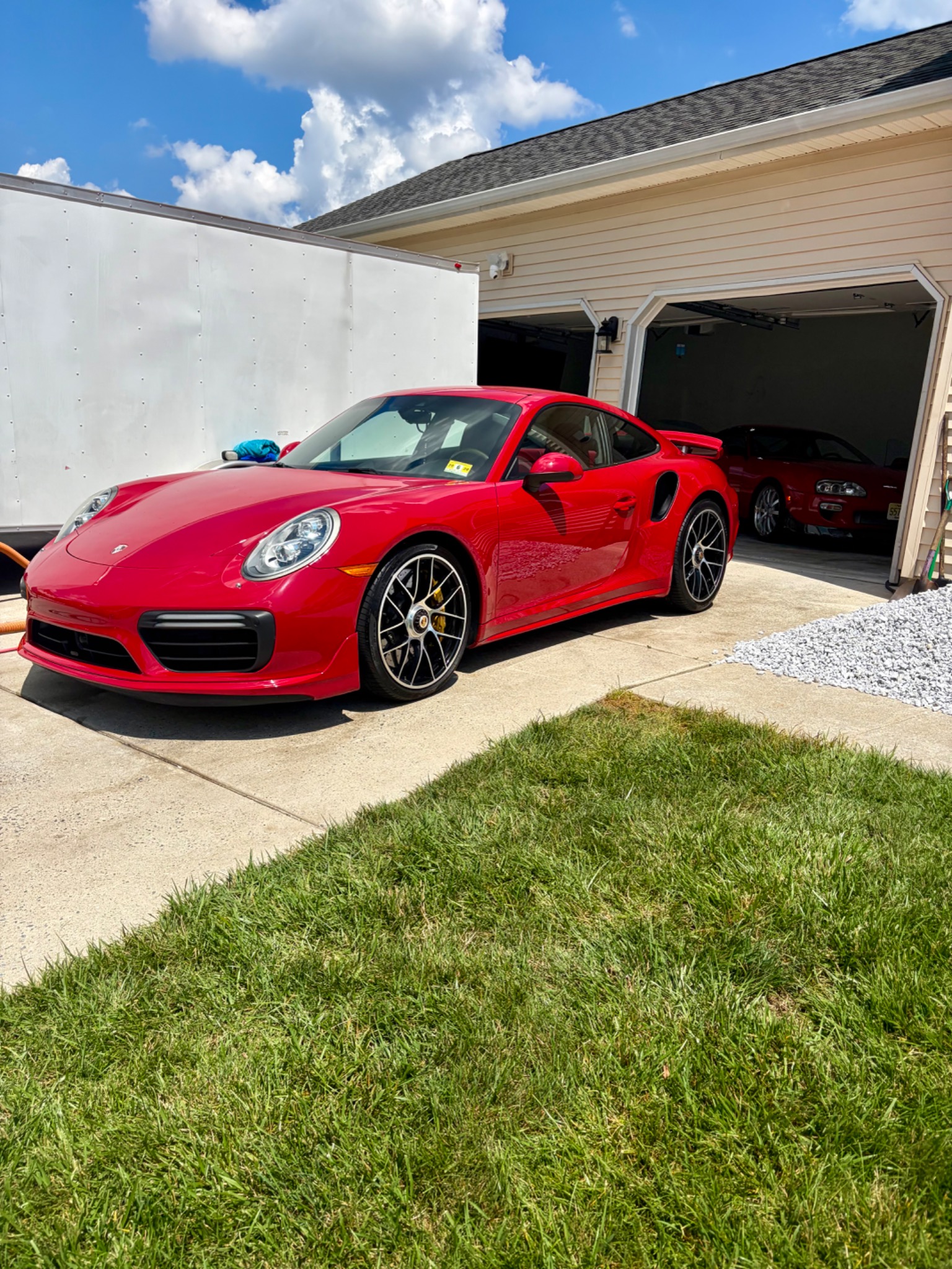 Red Porsche 911 parked outside a garage after maintenance detailing.