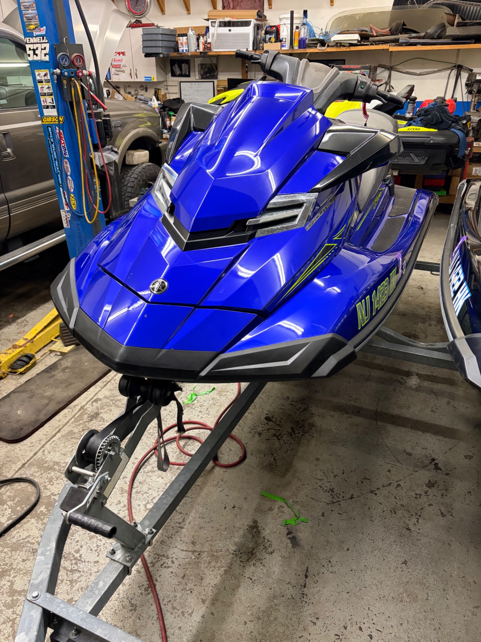 Glossy blue Yamaha personal watercraft on a trailer inside the shop after a wash and wax.