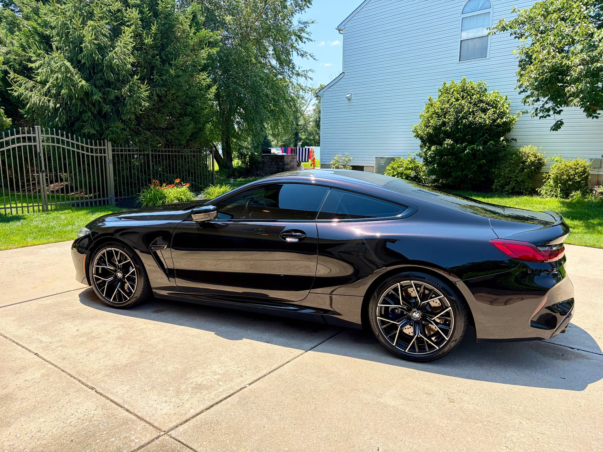 Black BMW M8 Competition coupe detailed to a mirror finish in a driveway.