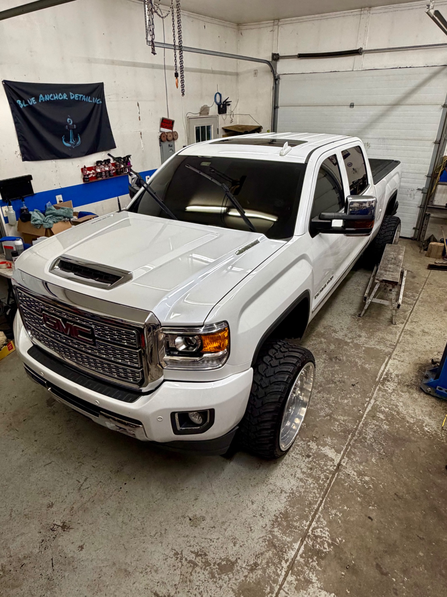 White GMC Sierra Denali HD with polished wheels inside the Blue Anchor detailing bay