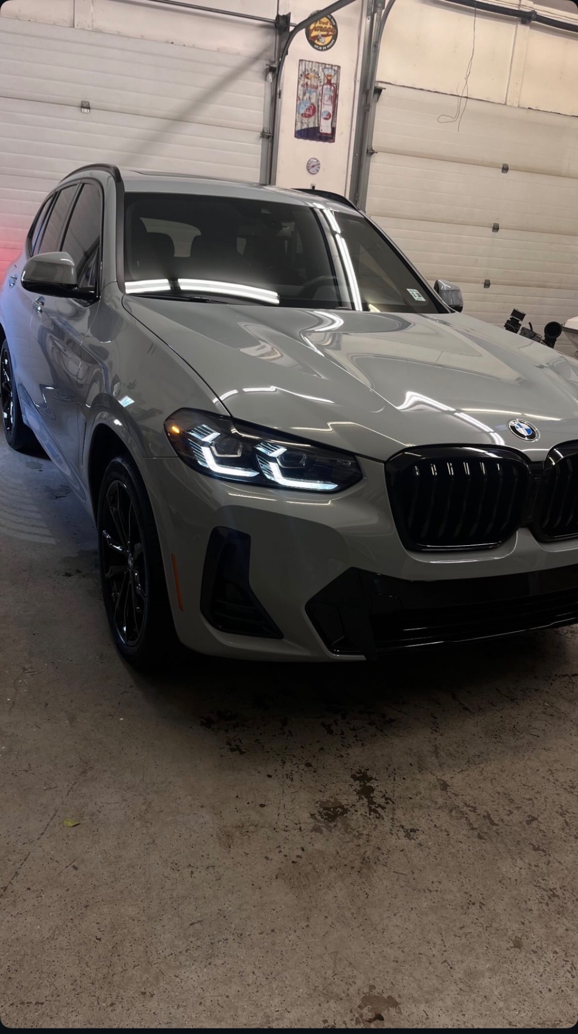 Grey BMW X3 with glossy paint and mirror-like reflections inside the detailing shop